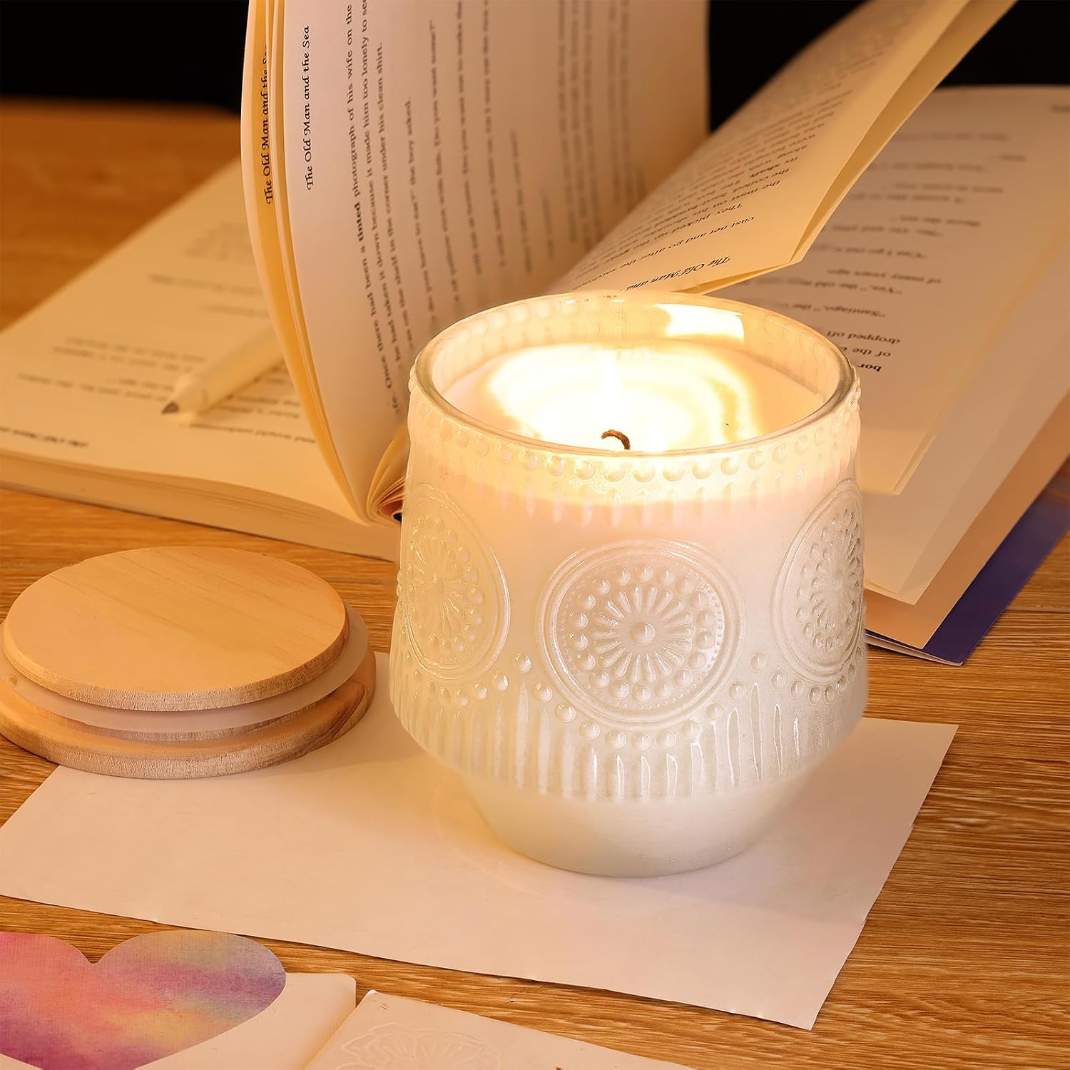 Floral glass candle beside an open book